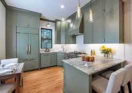 Kitchen cabinets refinished in soft sage green with a painted range hood