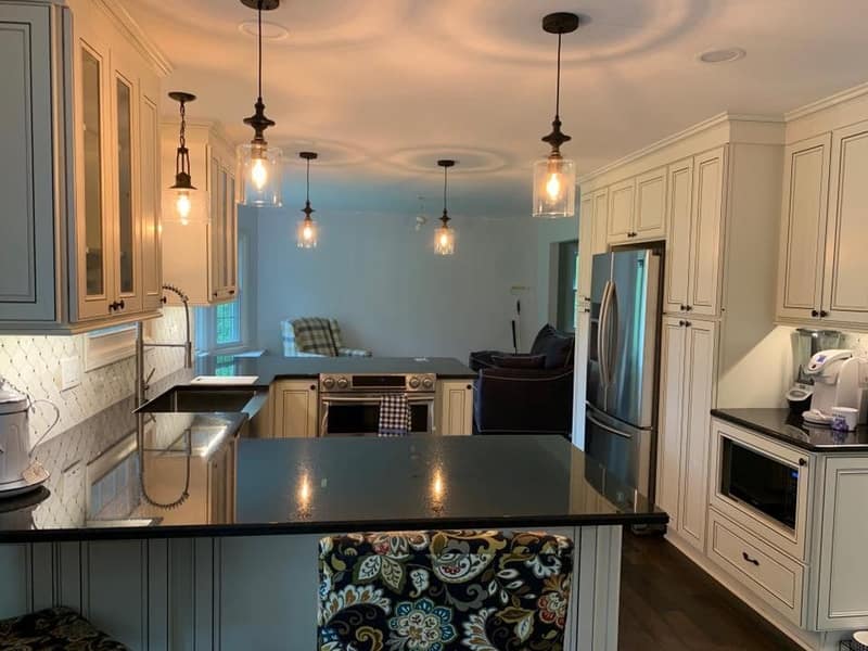 Kitchen remodel with cream cabinets, pendant lights and dark countertops