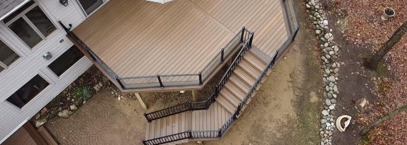 Composite deck with railing lighting overlooking a wooded lot at dusk