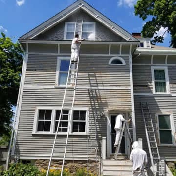 Crew prepping and painting a home exterior in Michigan